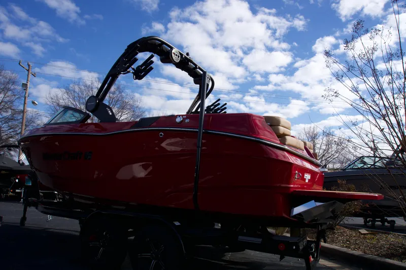 Slide: The Image of 2025 MasterCraft XT22T boat, red exterior, parked under a blue sky with clouds. - 3