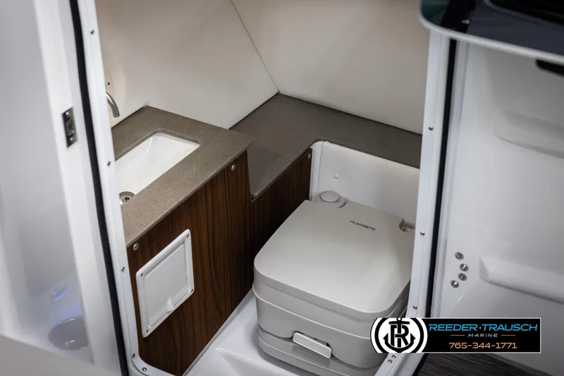 Slide: The Image of 2025 Four Winns HD5 boat interior with compact bathroom, featuring a sink and portable toilet. - 27