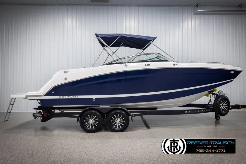 Slide: The Image of 2025 Four Winns HD5 boat with blue hull on trailer in showroom. - 5