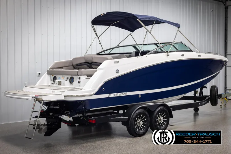 Slide: The Image of 2025 Four Winns HD5 boat with blue hull on trailer in showroom. - 6