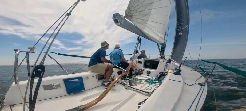 Slide: The Image of Sailors navigating a 2006 J Boats J/92S yacht on open water under clear skies. - 0