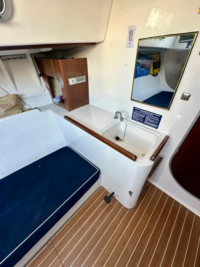 Slide: The Image of 2006 J Boats J/92S interior with sink, mirror, and blue cushioned seating. - 28