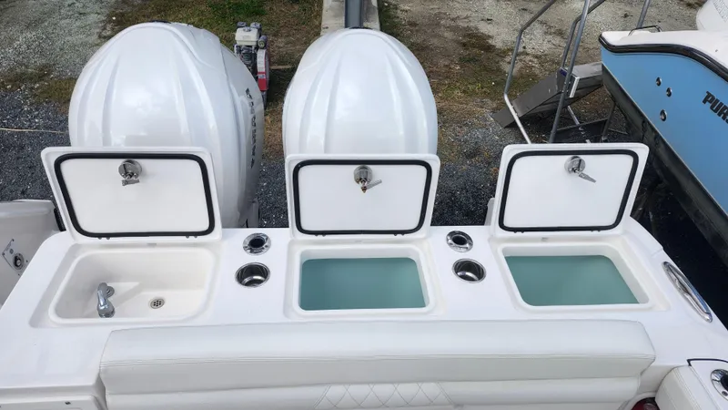Slide: The Image of 2023 Edgewater 280 CX boat with open storage compartments and dual engines. - 13