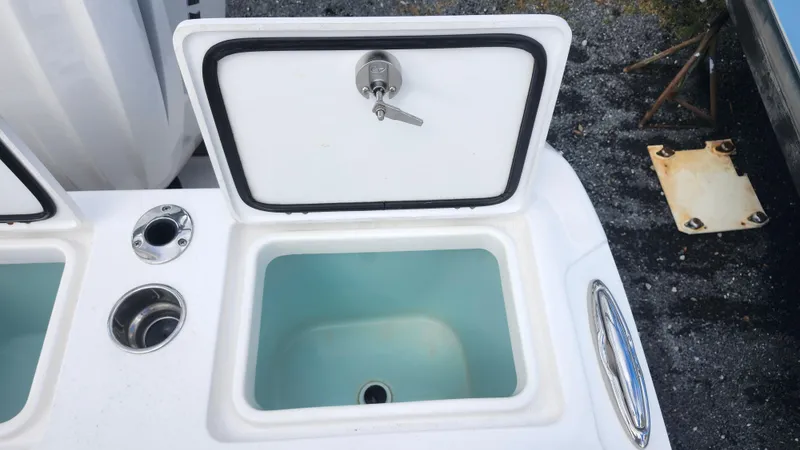 Slide: The Image of Edgewater 280 CX 2023 boat livewell with open lid and drain plug. - 16