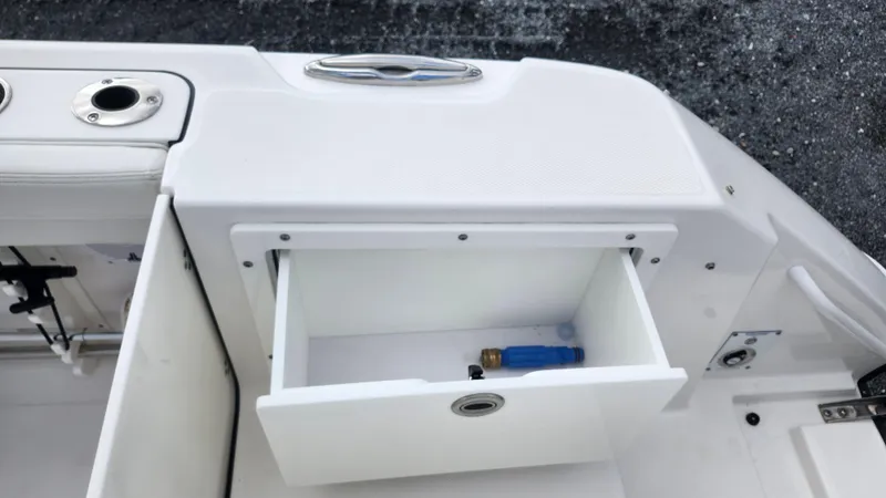 Slide: The Image of Open storage compartment on 2023 Edgewater 280 CX boat with a lighter inside. - 17