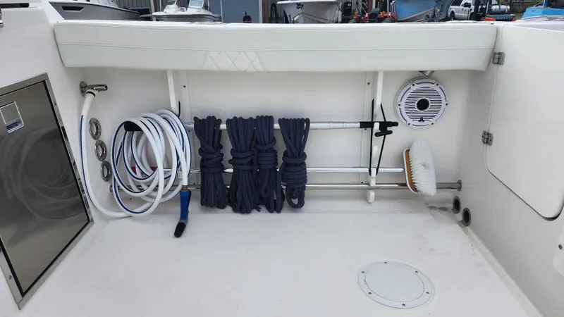 Slide: The Image of 2023 Edgewater 280 CX boat deck with organized ropes and cleaning supplies. - 23