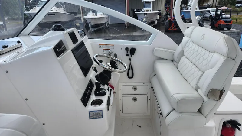Slide: The Image of 2023 Edgewater 280 CX boat cockpit with steering wheel and cushioned seating. - 37