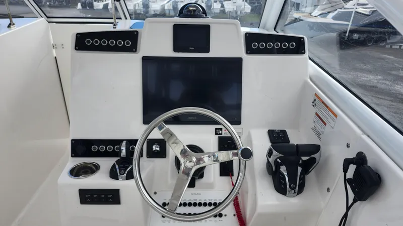 Slide: The Image of Edgewater 280 CX 2023 boat dashboard with steering wheel and control panel. - 40
