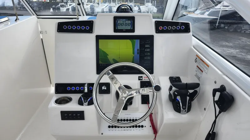 Slide: The Image of Edgewater 280 CX 2023 boat dashboard with steering wheel and navigation display. - 44