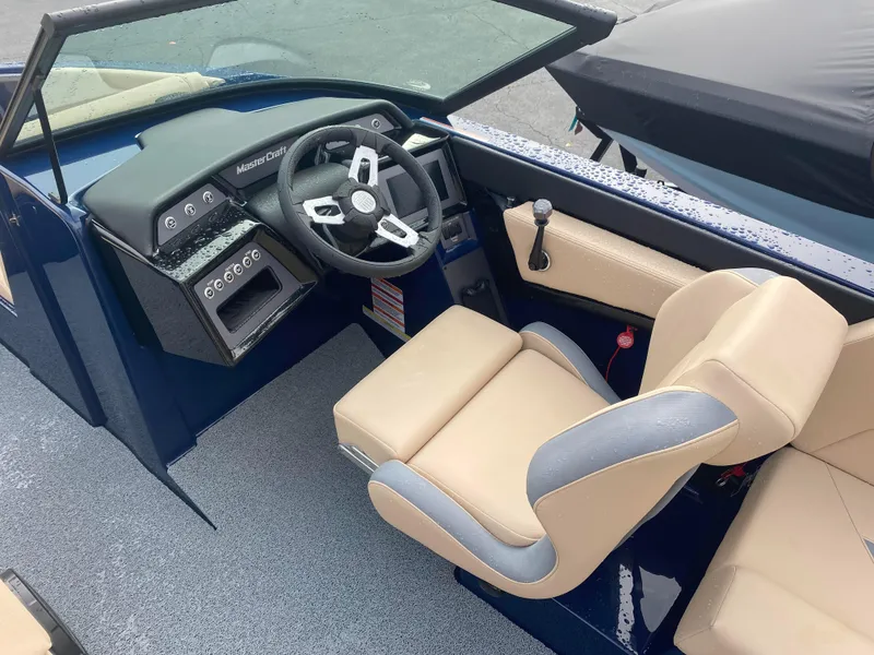 Slide: The Image of 2025 MasterCraft NXT21 boat interior with beige and gray seating, modern dashboard, and steering wheel. - 5