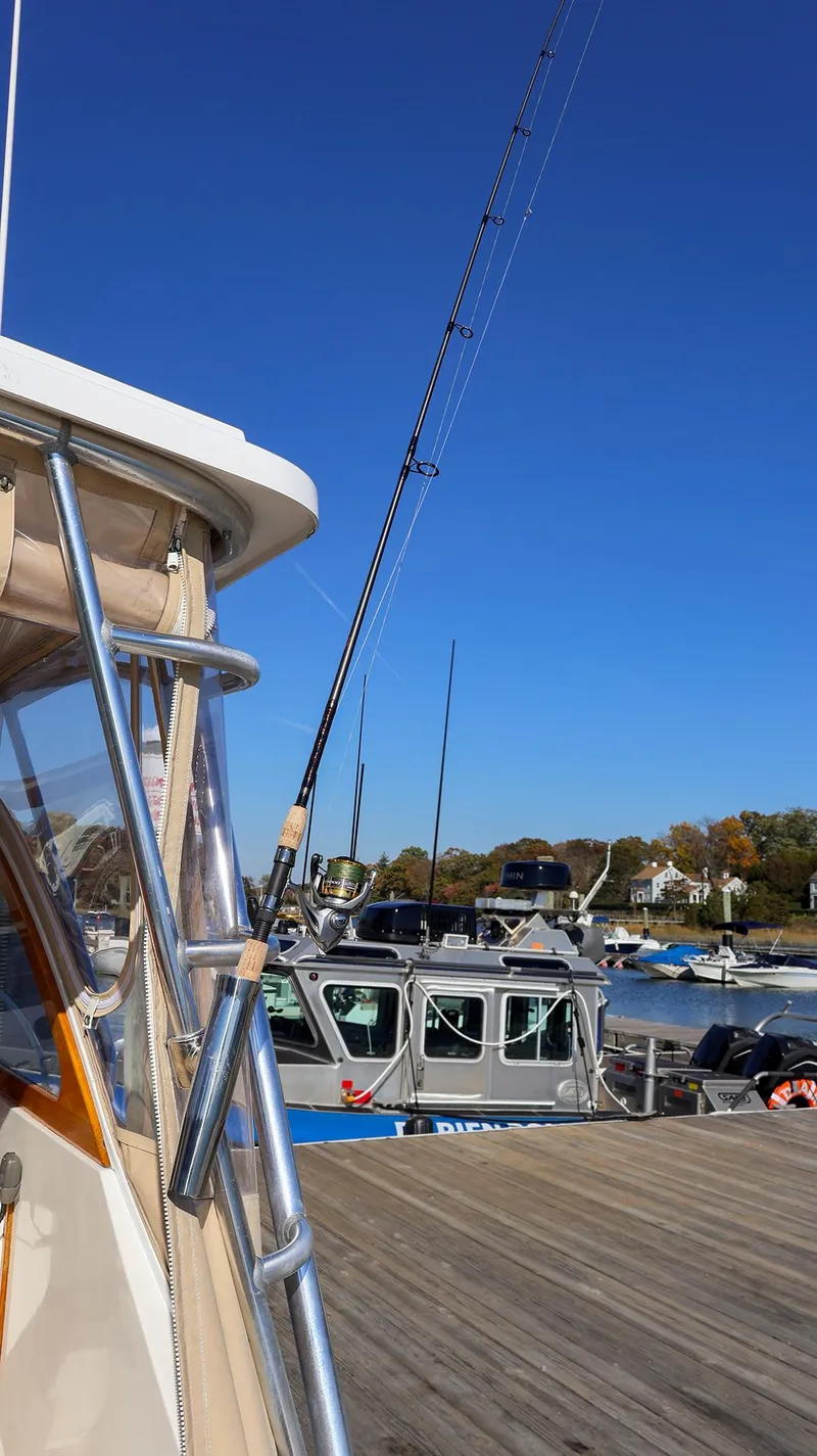Slide: The Image of Fortier 33 boat docked, fishing rods visible, clear blue sky, 2008 model. - 11