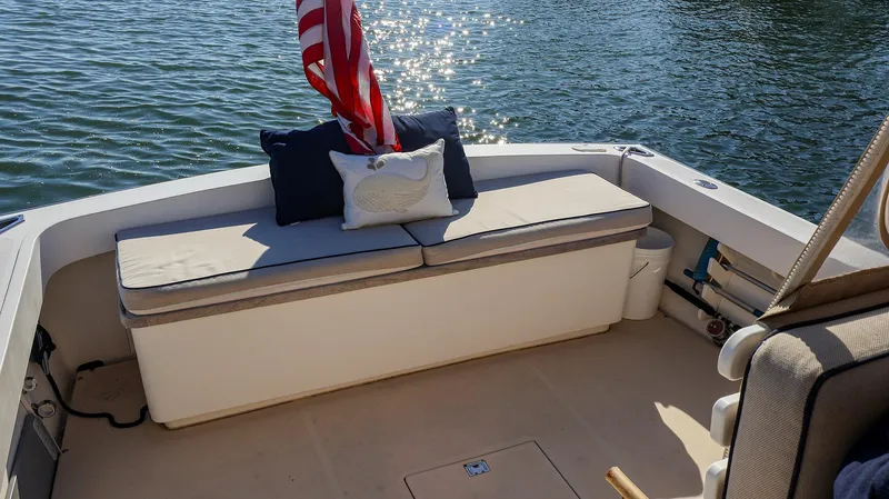 Slide: The Image of 2008 Fortier 33 boat with cushioned seating and American flag on calm water. - 18