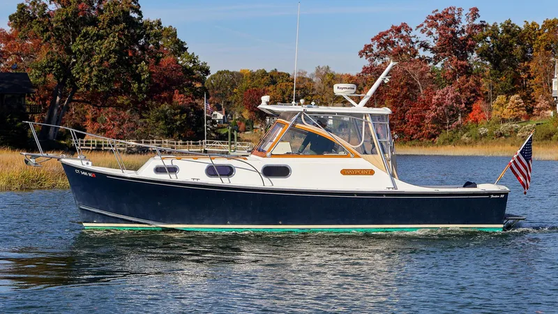 Slide: The Image of 2008 Fortier 33 boat cruising on a scenic lake with autumn foliage. - 2