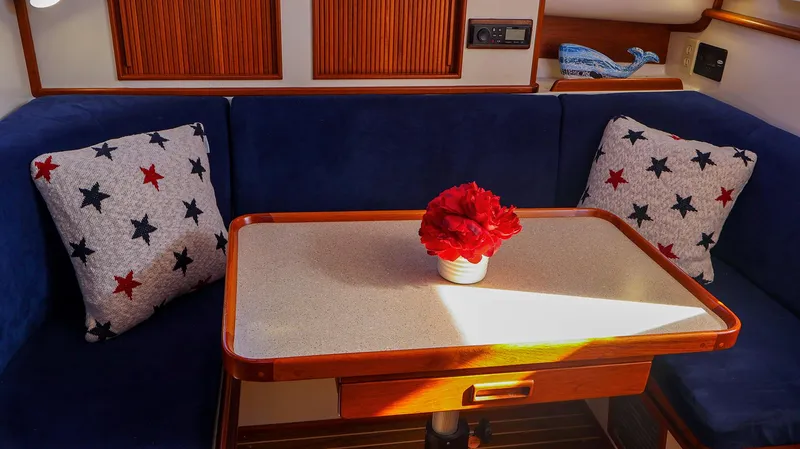 Slide: The Image of Cozy Fortier 33 boat interior with blue seating, star-patterned pillows, and a table centerpiece. - 26
