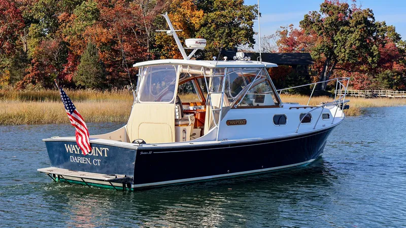 Slide: The Image of 2008 Fortier 33 boat on water, American flag, autumn trees in background. - 3