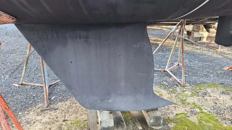 Slide: The Image of Keel of 2007 Alerion Express 28 sailboat on stands, gravel and grass background. - 9