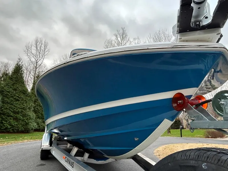 Slide: The Image of 2025 Caymas 26 HB boat on trailer, blue hull, overcast sky background. - 11
