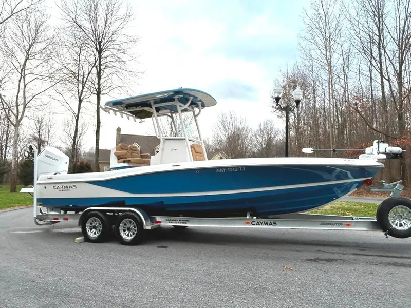 Slide: The Image of 2025 Caymas 26 HB boat on trailer, parked on a road with trees in the background. - 12