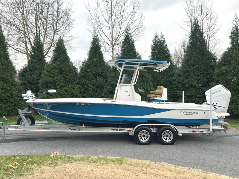 Slide: The Image of 2025 Caymas 26 HB boat on trailer, parked outdoors with trees in background. - 13