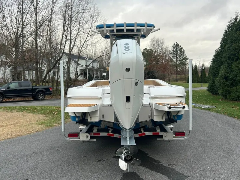 Slide: The Image of 2025 Caymas 26 HB boat with powerful outboard motor, parked on a driveway. - 16