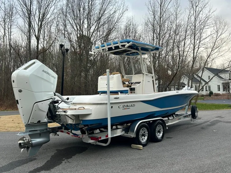 Slide: The Image of 2025 Caymas 26 HB boat on trailer, parked outdoors, featuring Mercury outboard engine. - 17