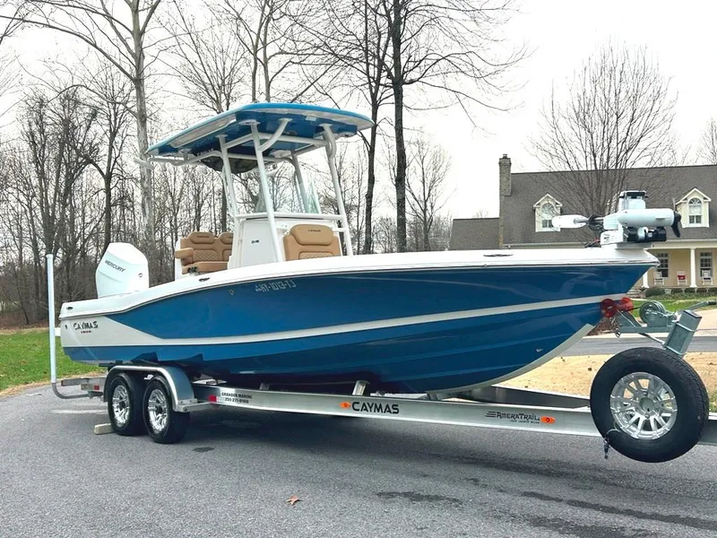 Slide: The Image of 2025 Caymas 26 HB boat on trailer, parked outdoors, showcasing sleek blue design. - 19