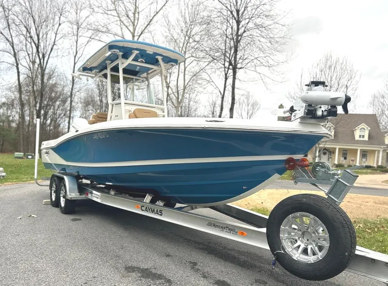 Slide: The Image of 2025 Caymas 26 HB boat on trailer, blue hull, parked outdoors. - 2