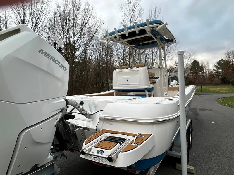 Slide: The Image of 2025 Caymas 26 HB boat with Mercury engine on a trailer, parked on a road. - 26