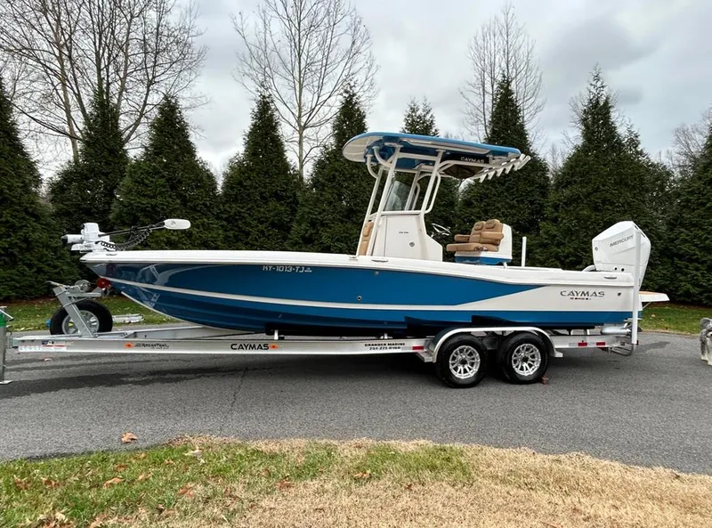 Slide: The Image of 2025 Caymas 26 HB boat on trailer, blue and white design, parked outdoors. - 3