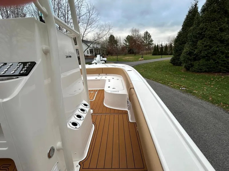 Slide: The Image of 2025 Caymas 26 HB boat with sleek deck design and wood finish, parked outdoors. - 30