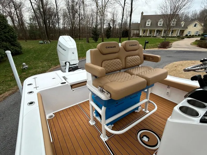 Slide: The Image of 2025 Caymas 26 HB boat with tan seating and Mercury engine in a suburban driveway. - 31