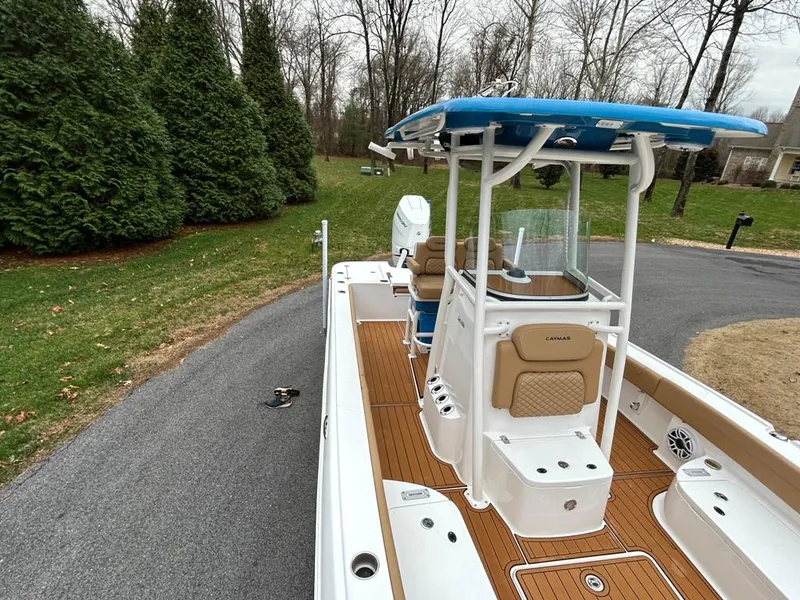Slide: The Image of 2025 Caymas 26 HB boat with blue canopy on a driveway, surrounded by trees. - 34