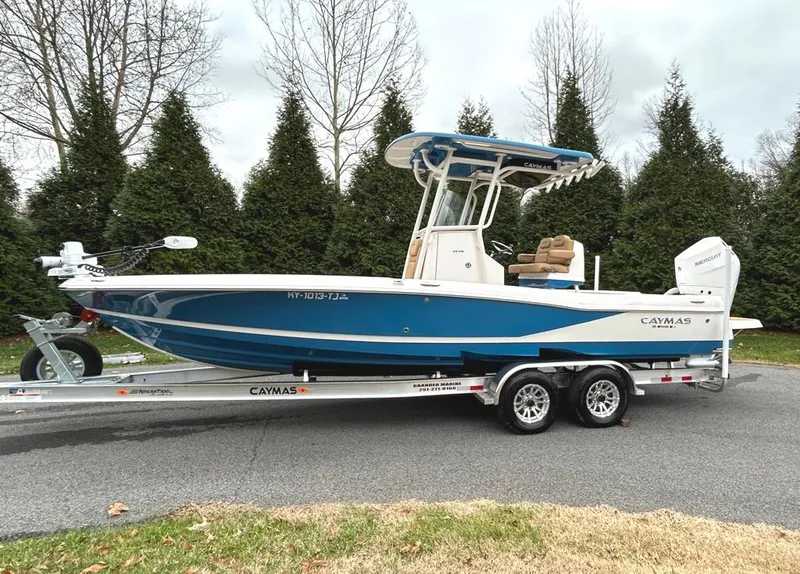 Slide: The Image of 2025 Caymas 26 HB boat on trailer, blue and white design, parked outdoors. - 4