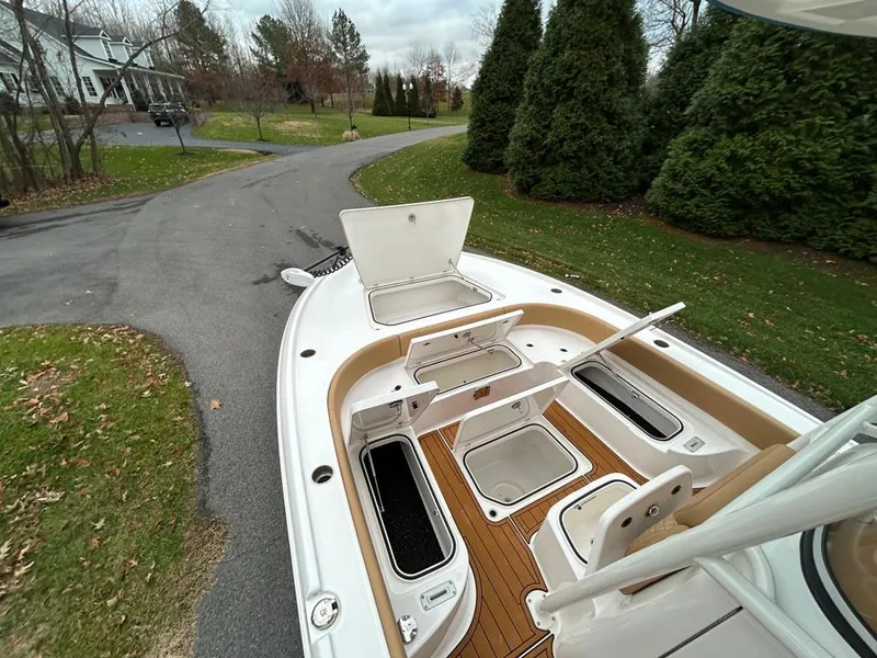 Slide: The Image of 2025 Caymas 26 HB boat with open storage compartments on a paved driveway. - 40