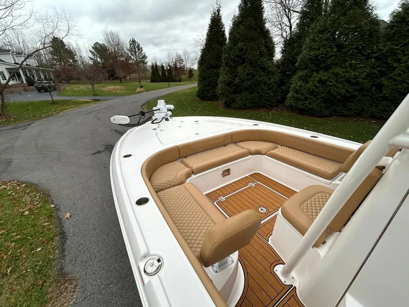 Slide: The Image of 2025 Caymas 26 HB boat with tan seating and wood deck, parked on a driveway. - 44