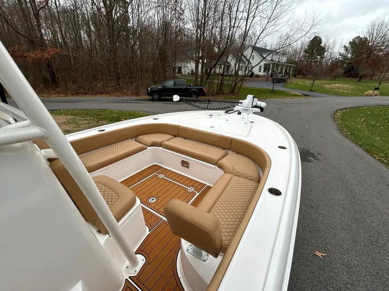 Slide: The Image of 2025 Caymas 26 HB boat with tan seating, parked on a driveway near trees and houses. - 45