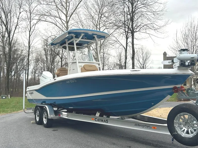 Slide: The Image of 2025 Caymas 26 HB boat on trailer, blue and white design, parked outdoors. - 6