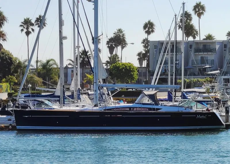 Slide: The Image of 2013 Jeanneau 57 yacht docked in a marina with palm trees in the background. - 1
