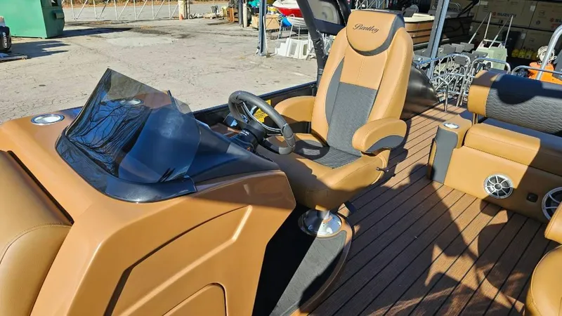 Slide: The Image of 2025 Bentley Pontoons Elite 253 Swingback interior with tan and black seating, steering console. - 2