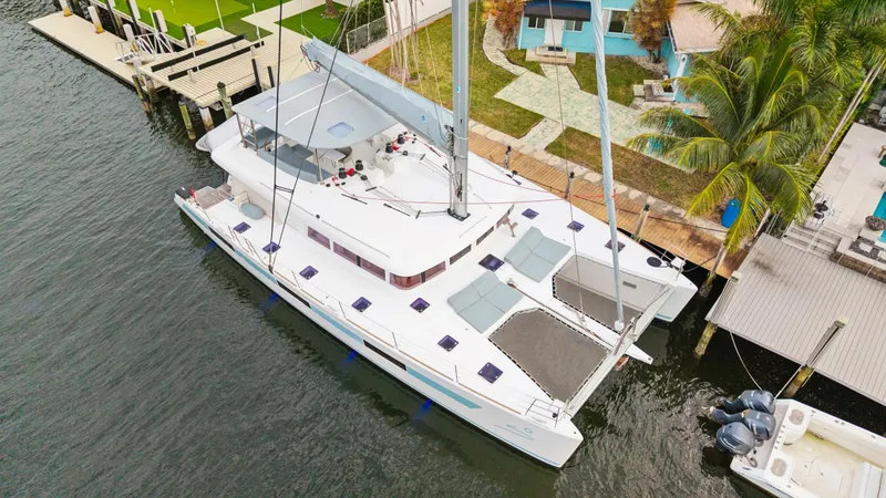 Slide: The Image of Aerial view of a 2014 Lagoon 620 catamaran docked by a waterfront property. - 13