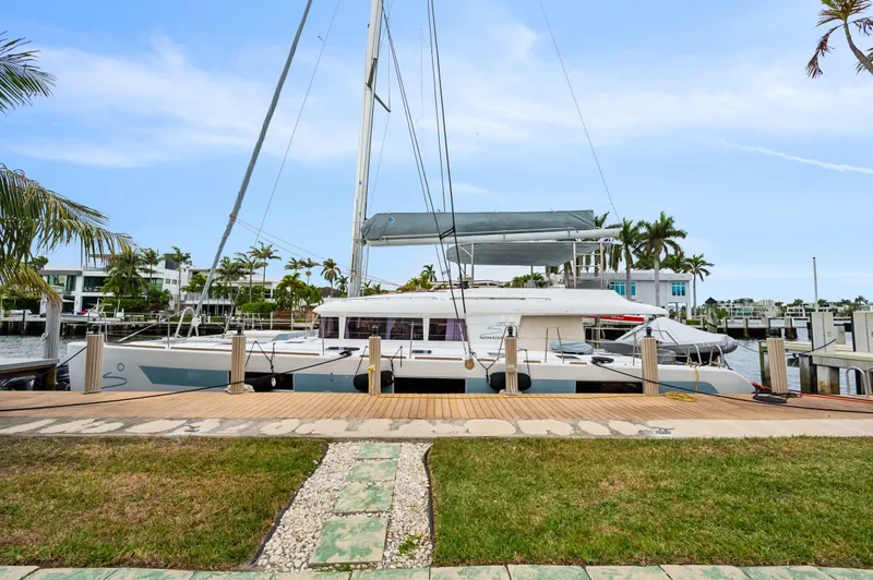 Slide: The Image of Lagoon 620 catamaran docked at marina, 2014 model, surrounded by palm trees and clear skies. - 14