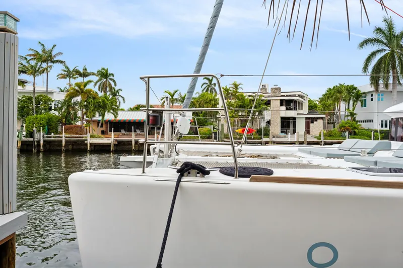 Slide: The Image of Lagoon 620 yacht docked by waterfront homes, surrounded by palm trees, 2014 model. - 15