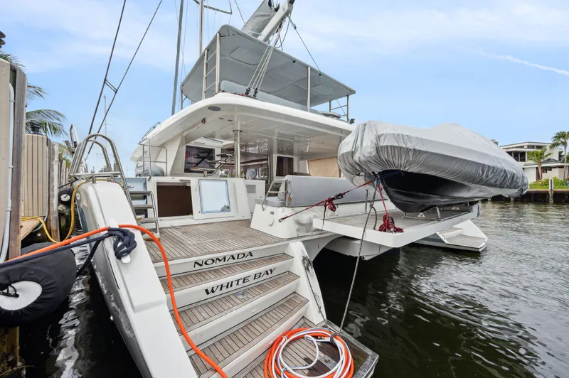 Slide: The Image of Lagoon 620 catamaran, 2014 model, docked with covered dinghy and visible deck area. - 16