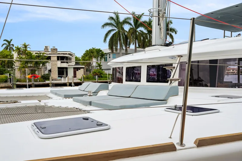 Slide: The Image of Lagoon 620 catamaran 2014, featuring spacious deck with sun loungers, docked near palm trees. - 20
