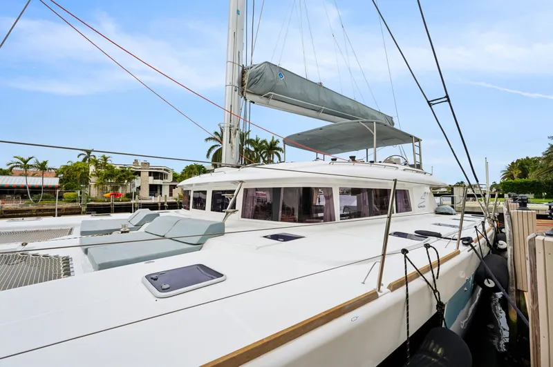 Slide: The Image of 2014 Lagoon 620 catamaran docked, featuring sleek design and spacious deck under clear skies. - 21