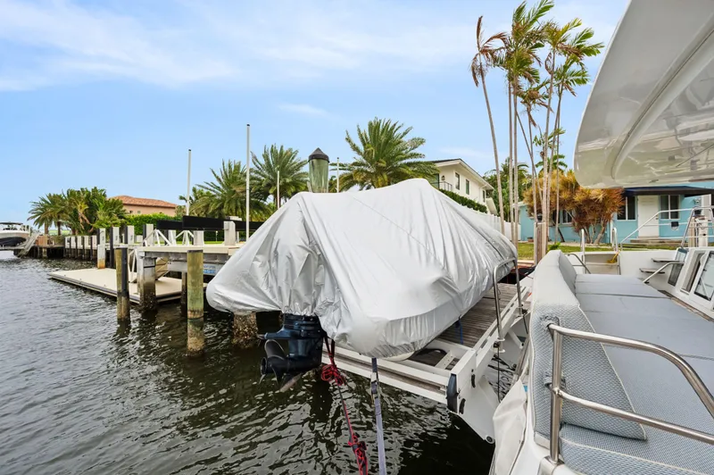 Slide: The Image of Lagoon 620 yacht docked by waterfront, covered boat nearby, palm trees in background. - 28