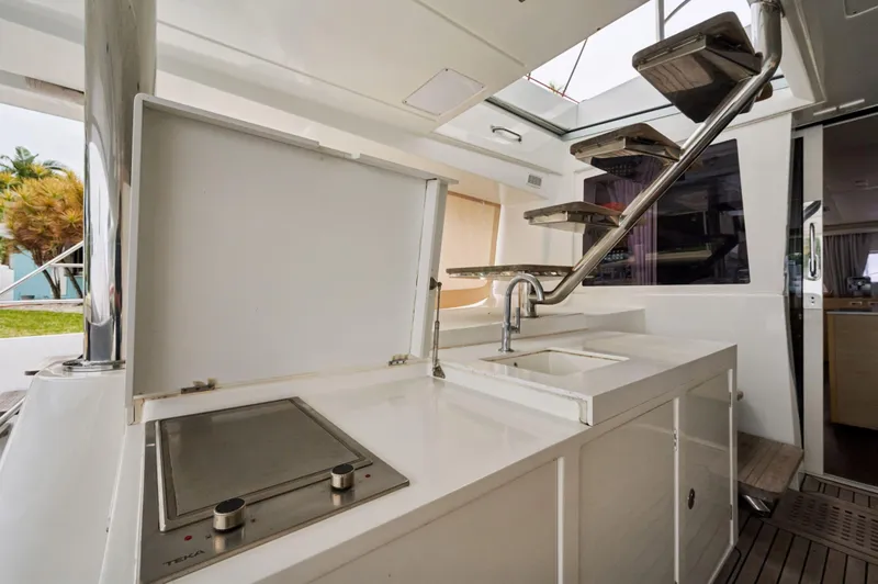 Slide: The Image of Outdoor kitchen area on a 2014 Lagoon 620 yacht, featuring a sink and stove. - 31