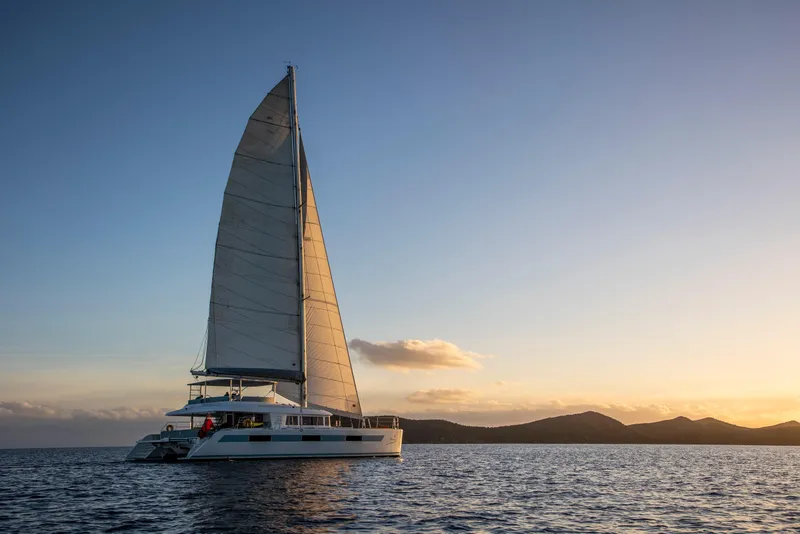 Slide: The Image of Lagoon 620 catamaran sailing at sunset, 2014 model, on calm ocean waters. - 6