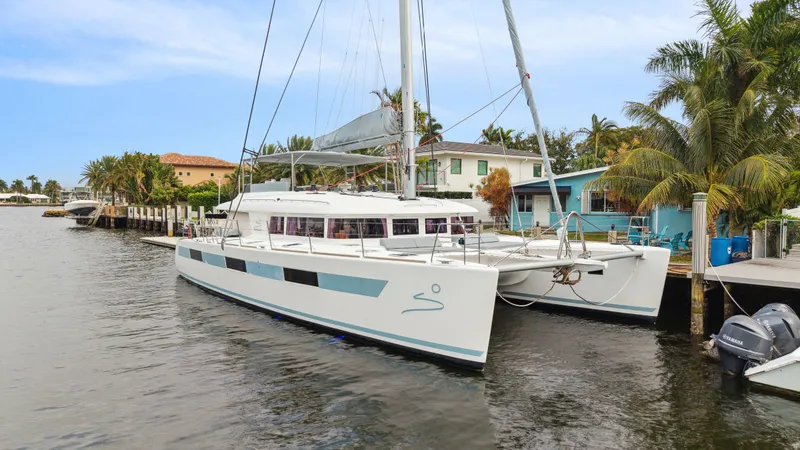 Slide: The Image of Lagoon 620 catamaran, 2014 model, docked by palm trees and waterfront homes. - 7
