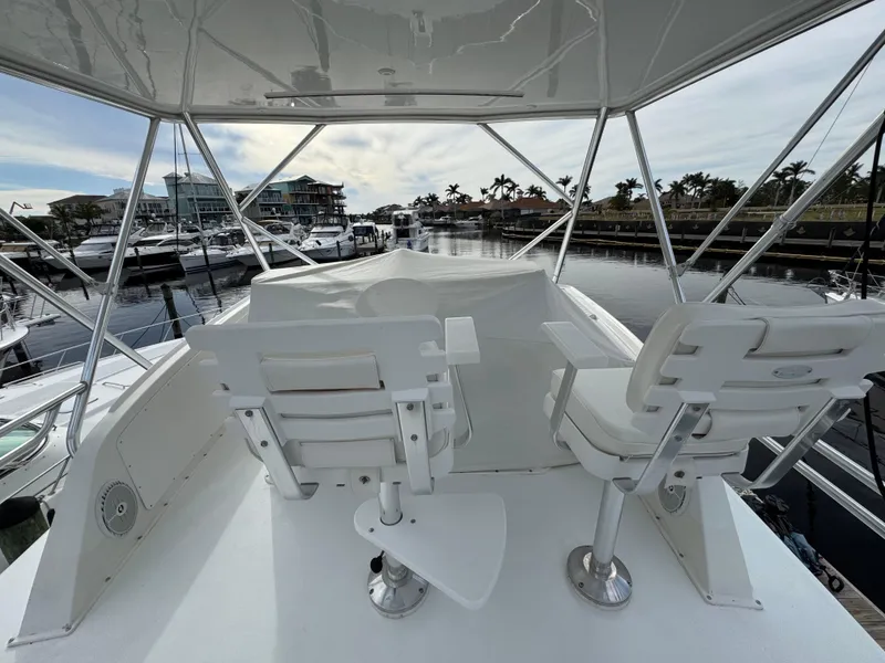 Slide: The Image of 1999 Cabo 45 Express yacht helm with two white captain chairs, marina view. - 26